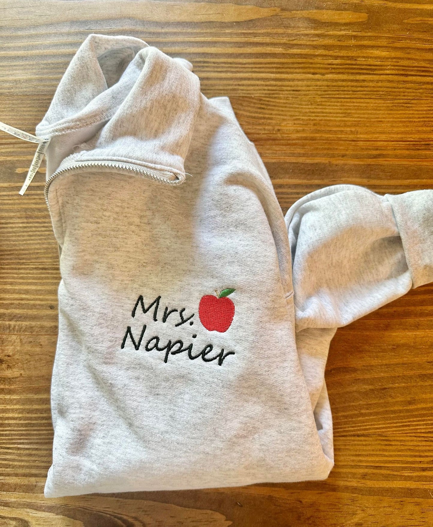 Embroidered Teacher name with Apple on Quarter Zip Sweater shown in the Color Ash - Flat Lay