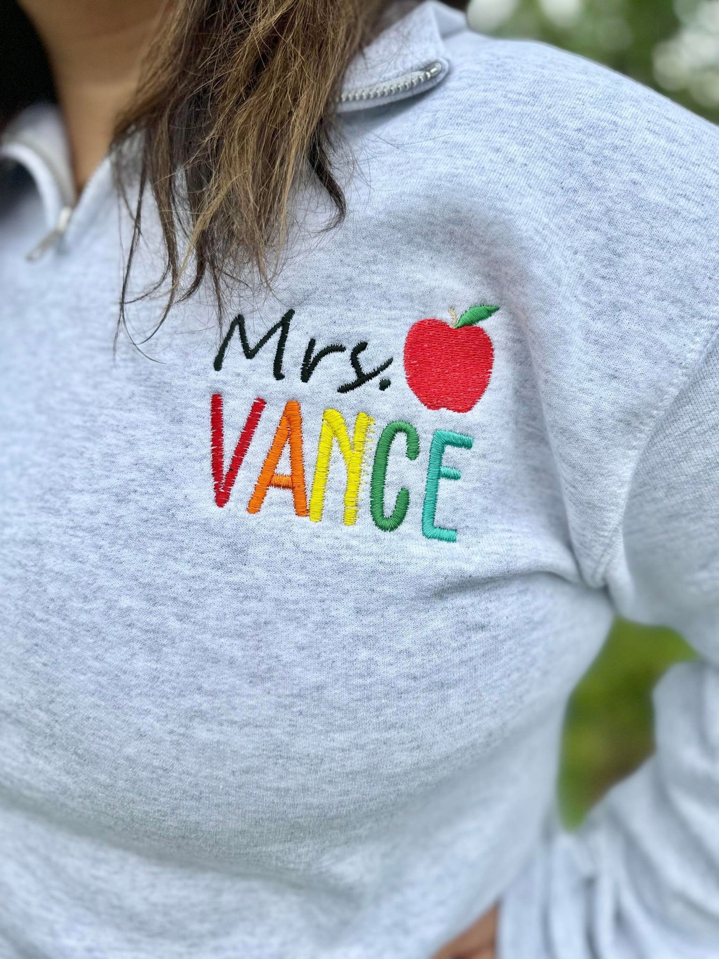 Personalized Teacher Name Quarter Zip Sweater Shown in Ash Color - Teachers name is Embroidered in Rainbow with an apple - On Model